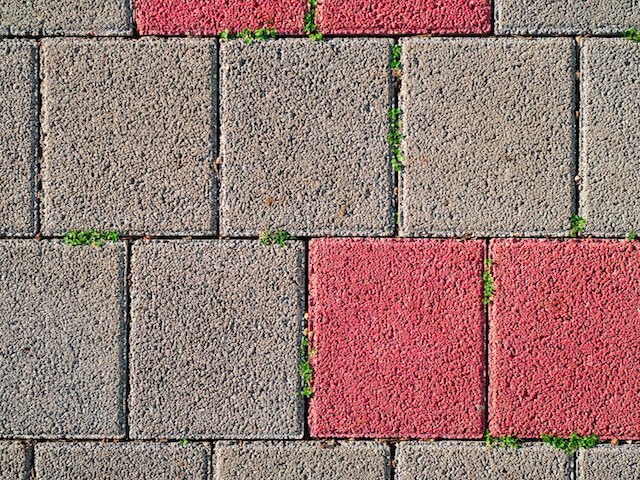 multi-colored-paving-slabs-tiny-green-grass-growing-them-top-view-red-gray-tiles-using-recycled-materials-create-tracks-improving-local-life_166373-1862